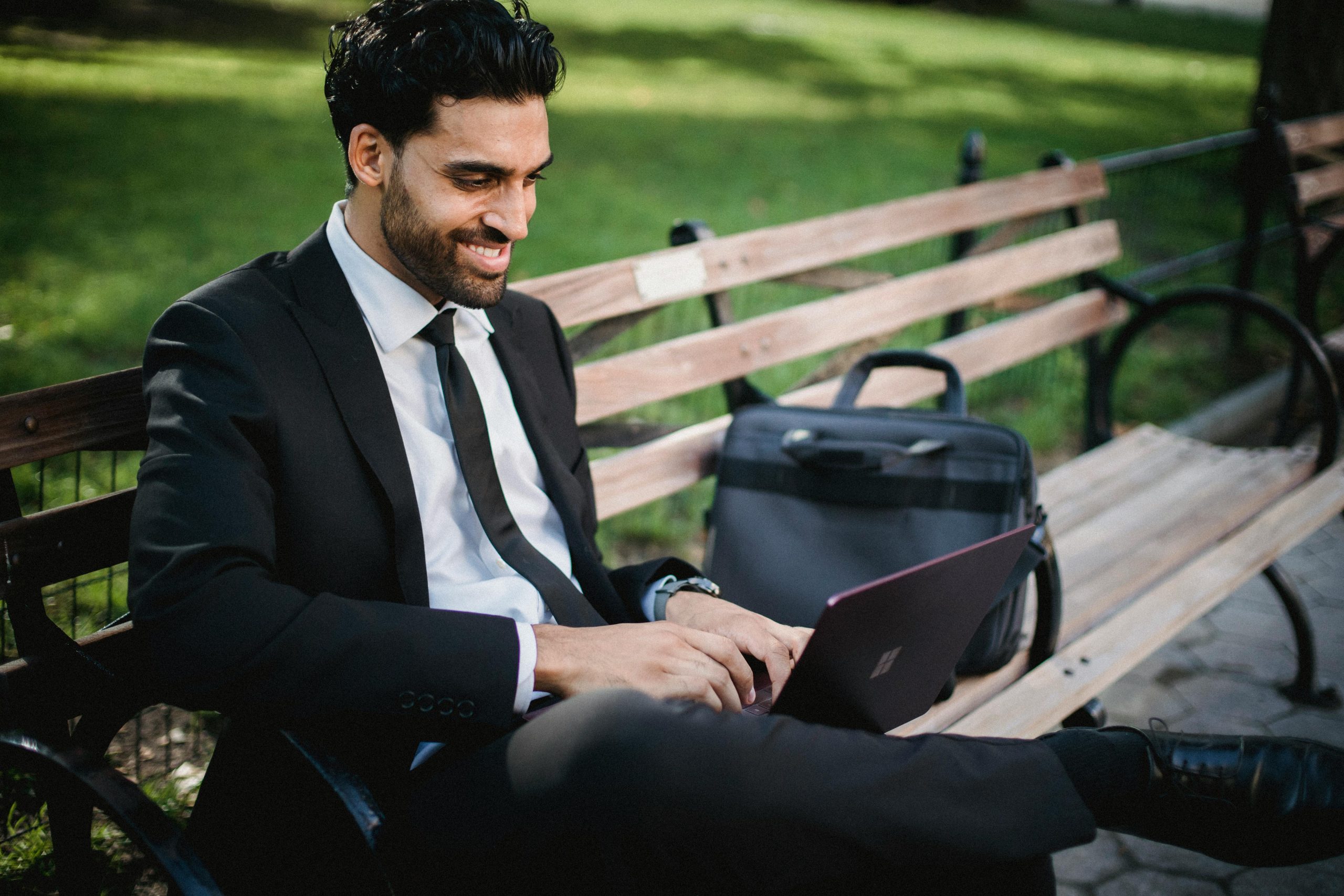 Schedule ADHD Support Coaching Professional smiling while working on a laptop outdoors, symbolising empowerment and productivity through ADHD coaching